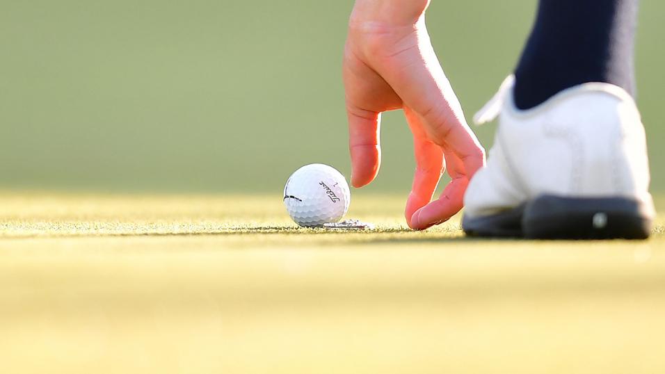 Golf player marks ball